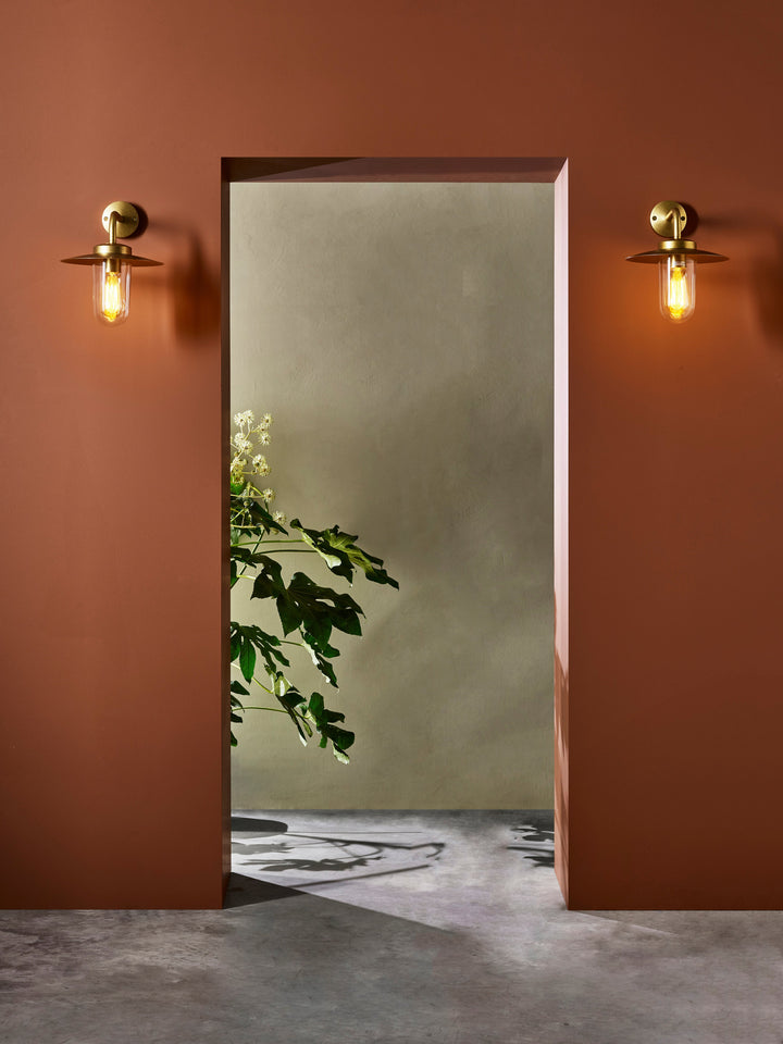 Astro Portree wall light installed beside doorway, casting warm downlight in outdoor setting